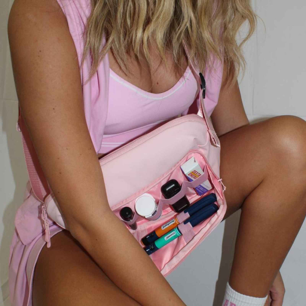 Woman wearing an open pink Betico Essential Diabetes Bag with organised diabetes supplies visible inside.