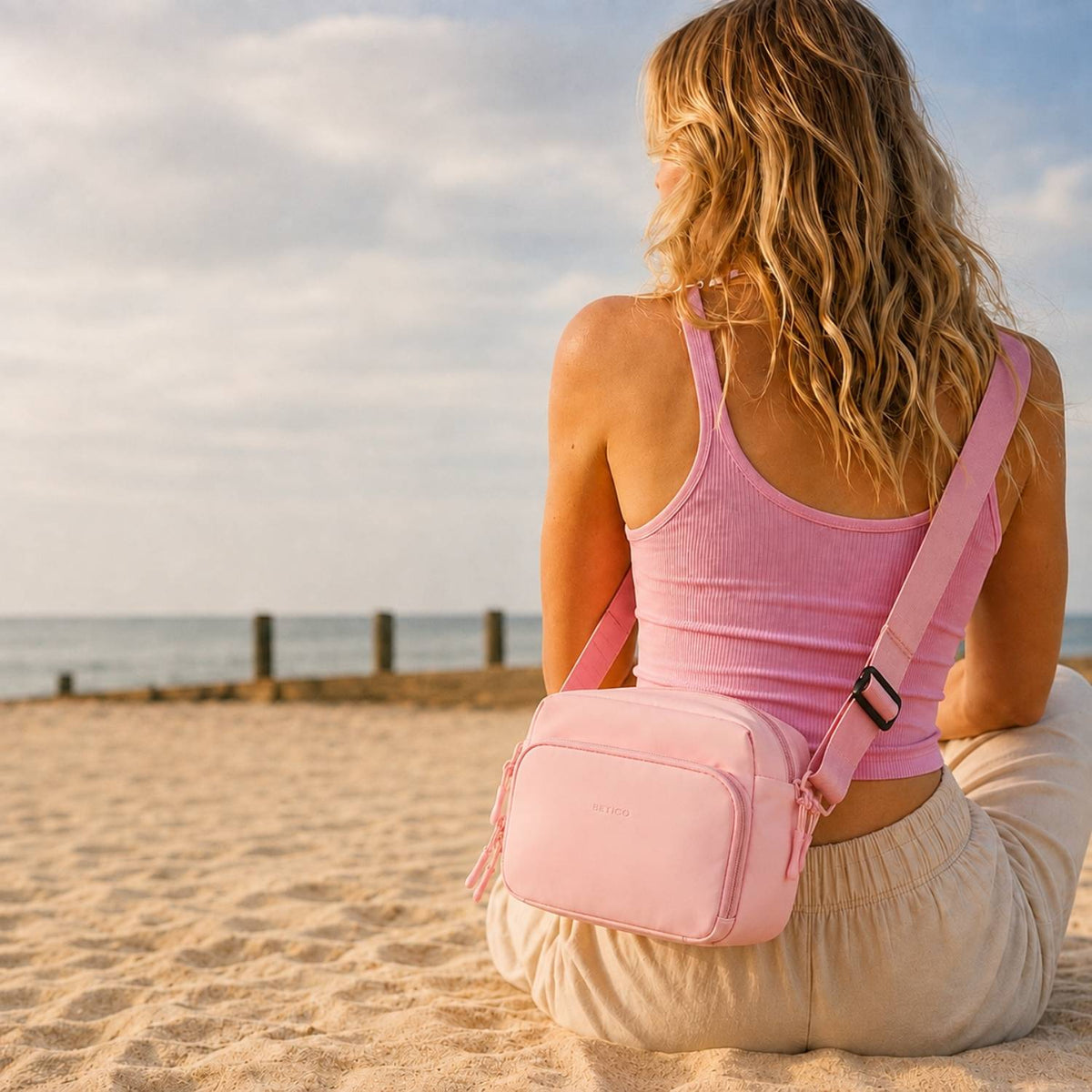 Betico Essential Diabetes Bag in Pink worn crossbody in a beach lifestyle setting